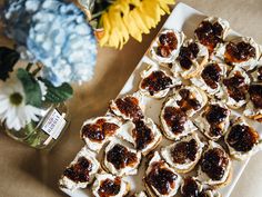 small pastries on a plate next to flowers and a jar of jelly in the background