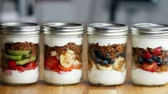 four mason jars filled with granola and fruit