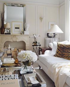 a living room filled with furniture and a fire place under a mirror on the wall