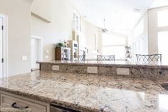 a large kitchen with marble counter tops and white cabinets