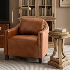 a brown leather chair sitting in front of a wooden book shelf with books on it