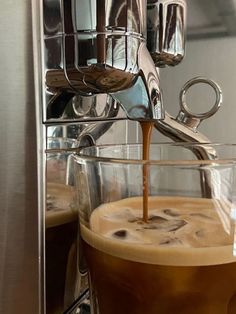 espresso being poured into a glass in front of an espresso machine