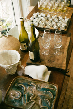 there are many wine glasses and bottles on the table next to each other, along with an assortment of pastries