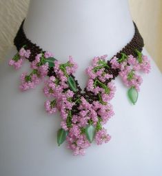 the necklace is adorned with pink flowers on a white mannequin headdress