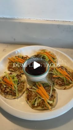 a white plate topped with three tacos covered in lettuce and carrots