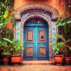 an ornate blue door surrounded by potted plants