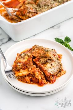 a white plate topped with lasagna next to a casserole dish filled with meat