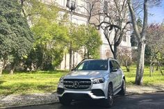 the mercedes gle is parked on the side of the road in front of some trees