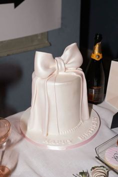 a white cake sitting on top of a table next to a bottle of wine and glasses