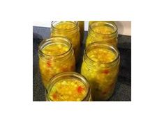 four jars filled with yellow liquid sitting on top of a counter next to each other