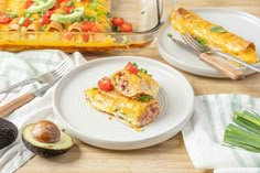 two white plates with food on them next to an avocado and bread dish