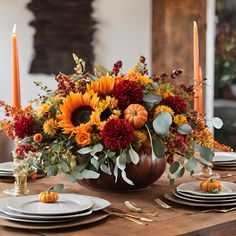 an arrangement of flowers and candles on a dining room table with place settings for four