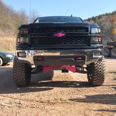 a large black truck parked on top of a dirt road