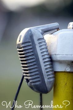 a yellow and white fire hydrant sitting on top of a green pole next to a field