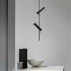 a white bowl sitting on top of a table next to a black lamp hanging from the ceiling