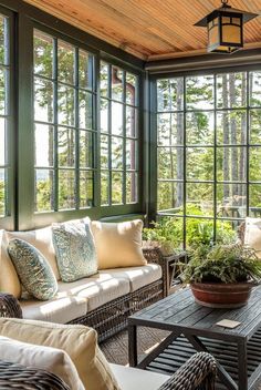 a living room filled with lots of windows next to a table and couch in front of it