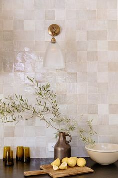 some lemons are sitting on a cutting board in front of a vase and bowl