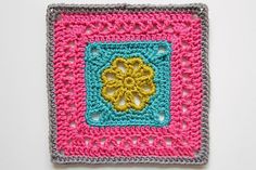 a crocheted square with a flower in the center on a white surface,