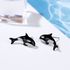 The Orca, commonly known as the Killer Whale, is a majestic creature often found raising above the waves and between icebergs.Our Orca earrings are made in sterling silver with black enamel and set with shimmering round stones.The overall effect is at once simple and stunning. Orca's signify romance, long life and protection. Black and white portrays life’s contrasts. This beautiful significance gives this pretty pair a meaningful dimension too. Carat Weight: 0.456 ctStone Size: 1.1,1.3,0.9 mmSt Sterling Silver Earrings With Black Enamel, Sterling Silver Round Earrings With Black Enamel, Sterling Silver Earrings With Black Enamel In Round Shape, Black Enamel Earrings, Pierced, Black Enamel Pierced Earrings, Black Enamel Nickel-free Earrings, Pokemon Jewelry, Killer Whale, Killer Whales