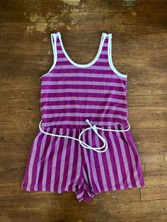 Ugh this is so cute but so short for my torsoAmazing 80’s striped romper Magenta purple and white striped romper Tank sleeves with cute buttons on top of sleeves Elastic waistline Ties around the waist it’s connected in back One pocket on one side Cotton polyester material Great vintage condition Short shorts Tag reads size medium Measurements are approximate and taken flat so please double bust waist and hips for more accurate sizing Bust: 15.5 in Waist: 15.5 in stretched to 17 in Hips: 19 in R Womens Jumpsuits, Cute Buttons, Magenta Purple, Linen Jumpsuit, Striped Rompers, Sporty Chic, Purple And White, Black Romper, 1980s Vintage