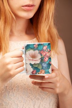 a woman is holding a mug with flowers on it