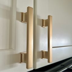 two brass handles on white cabinets in a kitchen