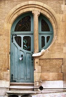 a green door on the side of a brick building with arched glass and stone steps