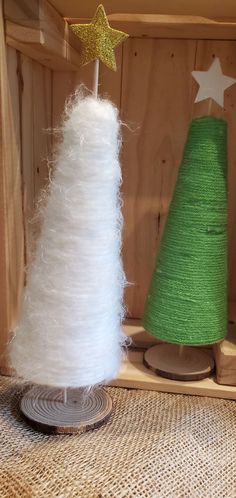 two white and green christmas trees in a wooden box with twine on the top