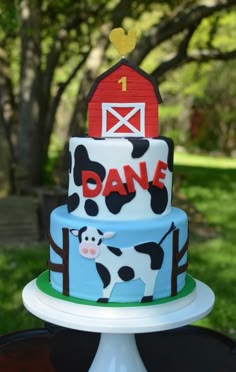 a cake with a cow on it and a barn in the background is sitting on a table