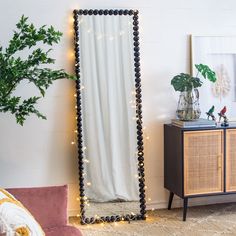 a mirror sitting on top of a wooden dresser next to a plant