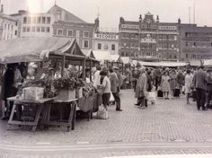 an old black and white photo of people shopping in a market place with buildings in the background