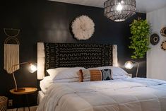 a white bed sitting in a bedroom next to a wall mounted plant and two lamps