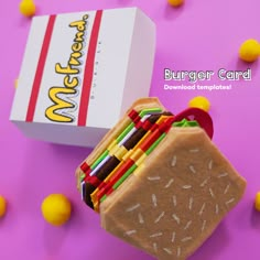 a small sandwich made out of colored pencils next to a mcdonald's box