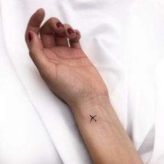 a woman's arm with a small airplane tattoo on it