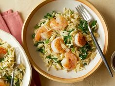 two plates of shrimp and rice with spinach garnish on the side next to silverware