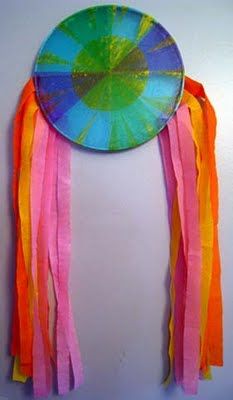 a colorful paper plate hanging on the wall with tassels around it's edges