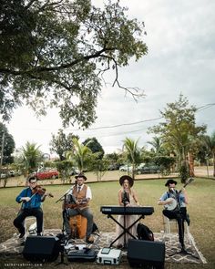 a group of people that are playing music on some kind of blanket in the grass