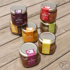 four jars of jam sitting on top of a wooden table