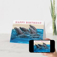 a person holding up a cell phone with a card in front of it that says happy birthday