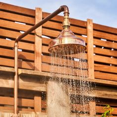 a shower head with water coming out of it and wooden slats in the background