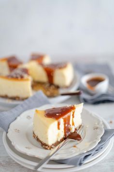 two slices of cheesecake with caramel sauce on top, sitting on plates next to each other