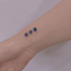 three small blue flowers on the left inner wrist tattoo design by artist markiek