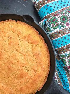 a baked cake in a cast iron skillet on a table with a blue and white napkin