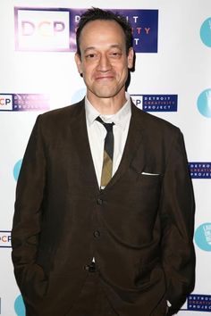 a man in a suit and tie posing for a photo on the red carpet at an event