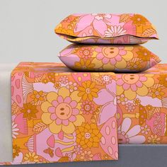 three pillows are stacked on top of each other in front of a gray background with pink and yellow flowers