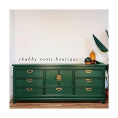 a green dresser sitting on top of a hard wood floor next to a white wall