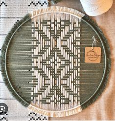 a green and white woven tray sitting on top of a table next to two balls of yarn