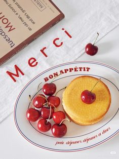 a plate topped with a cake covered in cherries next to a stack of books