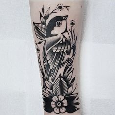 a black and white bird tattoo on the right arm, with flowers around its neck