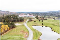 an aerial view of a golf course with a large white building in the background and trees surrounding it